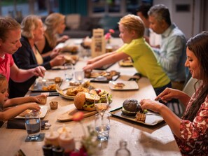 A group of people dining at a long table with various dishes and drinks. - Cozy Lodge With a Dishwasher in the Achterhoek (Winterswijk - Brinkheurne)