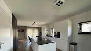 A modern kitchen with a central island, a dining area with chairs, and a small bar area. - Country House with Terrace near Langweerder Wielen (Sint Nicolaasga)