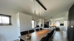 A modern kitchen with a long dining table, black chairs, and pendant lights. - Country House with Terrace near Langweerder Wielen (Sint Nicolaasga)