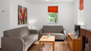 A living room with two sofas, a coffee table, a TV stand, and a window with a view of greenery. - Forest Stay With Shared Pool (Borger)