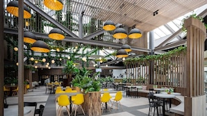 A spacious indoor dining area with high ceilings, modern pendant lighting, and a mix of yellow and black chairs. - Nice Villa With a Sauna in Limburg (Roggel)