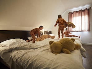 Une chambre à coucher avec un grand lit, une table de chevet, une lampe et une fenêtre avec des rideaux.