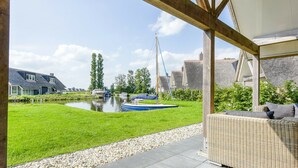 Eine überdachte Terrasse mit Blick auf einen Kanal, Boote und Häuser im Hintergrund.