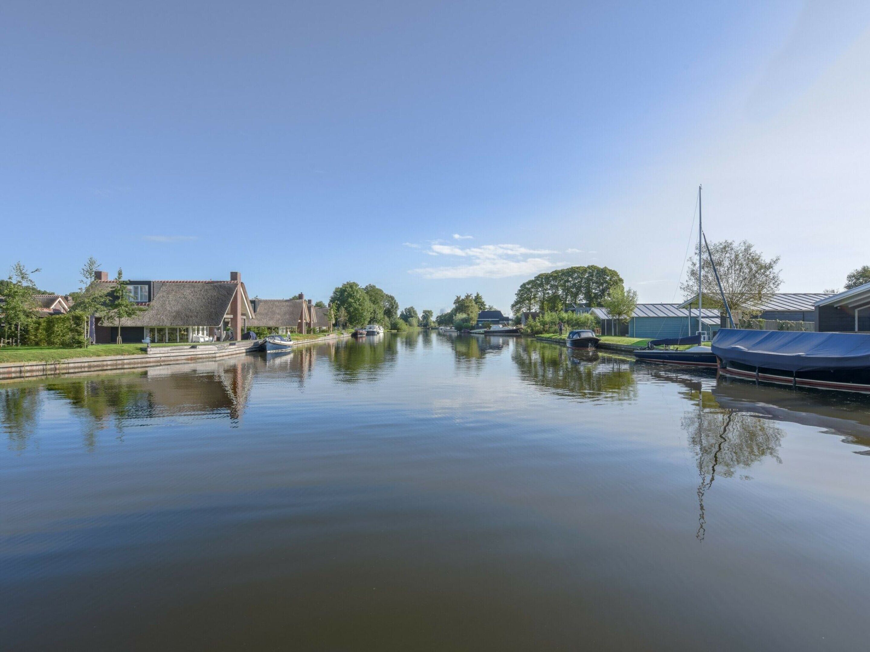 Un canal tranquilo con barcos, casas tradicionales y cielo despejado.