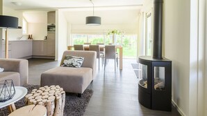 Ein modernes Wohnzimmer mit Kamin, Essbereich und Küche.