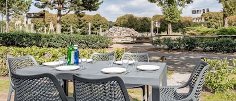 An outdoor dining area with a table set for four, surrounded by chairs.