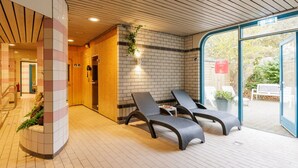 A spa area with a wooden floor, a brick wall, and two lounge chairs. - Forest Trails & Swimming Fun (Borger)