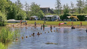 A lakeside campsite with tents, a grassy area, and people engaging in water activities. - Holiday House in Friesland With Garden (Sint Nicolaasga)