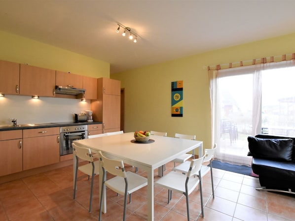 A modern kitchen with white cabinets, a dining table with chairs, and a black leather sofa. - Tolles Ferienhaus fur bis zu 15 Personen, Zierow (Zierow)