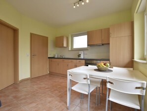 A compact kitchen with wooden cabinets, a white table, and chairs. - Tolles Ferienhaus fur bis zu 15 Personen, Zierow (Zierow)