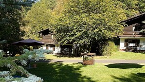 A lodge with multiple rooms, a large tree, and a well-maintained lawn. - Feriendorf Reinskopf in der Eifel (Schoenecken)