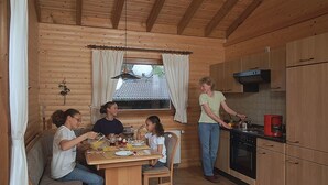 A wooden cabin interior with a dining area and kitchen. - Feriendorf Reinskopf in der Eifel (Schoenecken)
