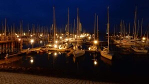 Een haven bij nacht, met tal van boten afgemeerd en verlicht door kunstlicht.