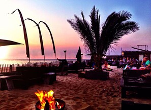 A beachside lounge with outdoor seating, a fire pit, and a view of the ocean at sunset. - Modified, Modern Lodge Near the Beach (Zandvoort)