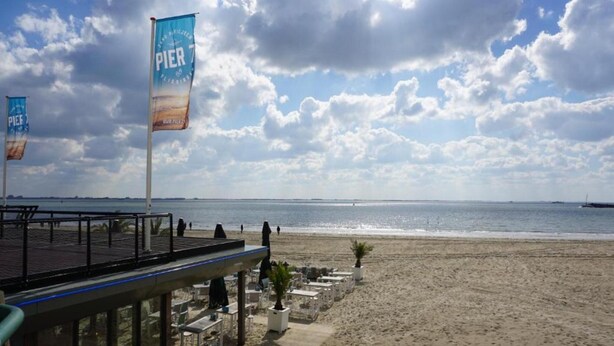 Un ristorante sulla spiaggia con posti a sedere all'aperto e vista sull'oceano.