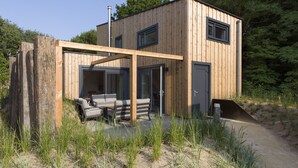 Una moderna cabina in legno con patio, posti a sedere integrati e un portico coperto.