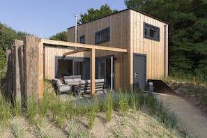 A modern wooden cabin with a patio area, built-in seating, and a covered entryway. - Lodge in Vlissingen Near North Sea Beach (Vlissingen)