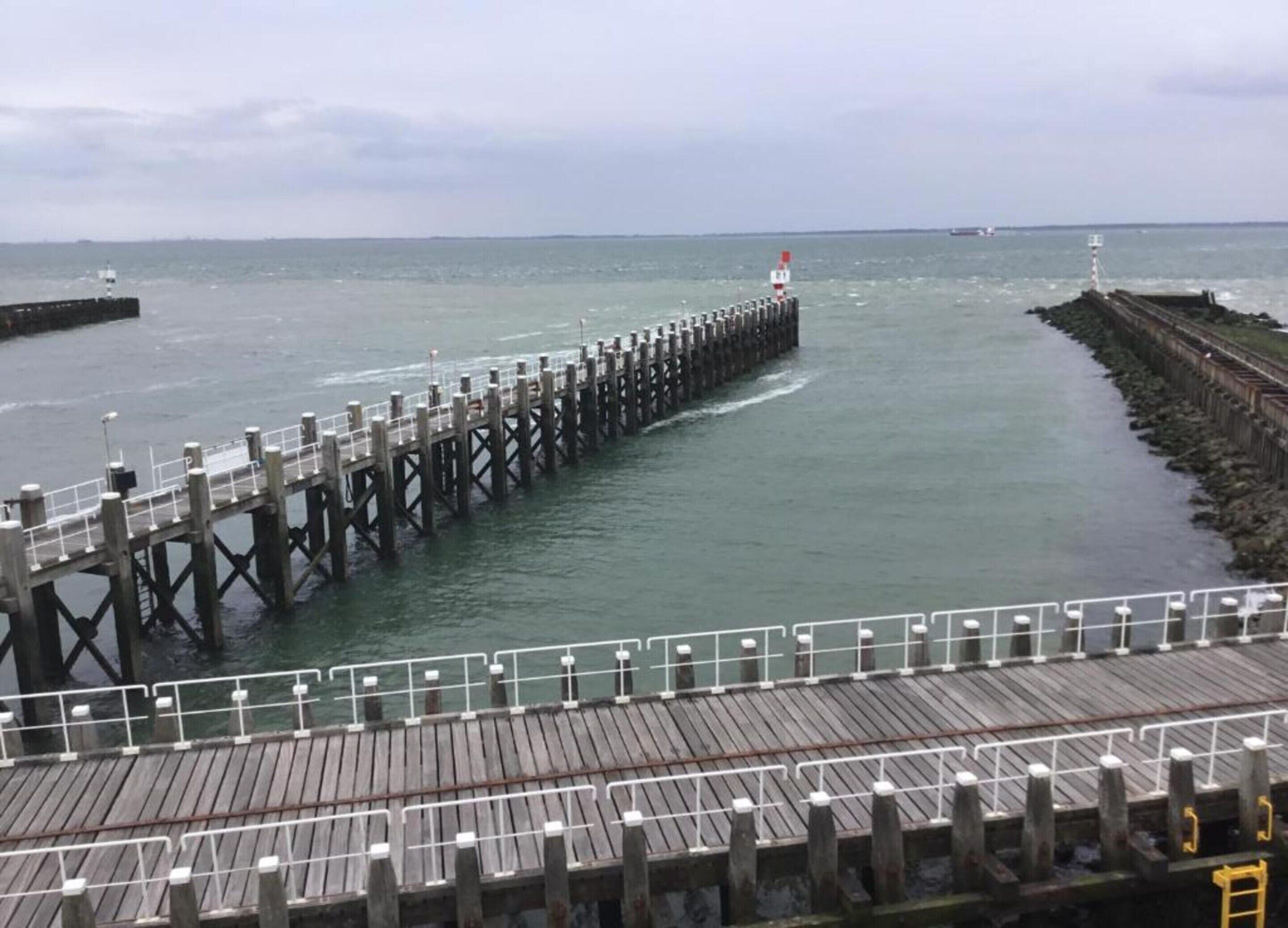 A pier extending into calm waters with a wooden walkway and railings.