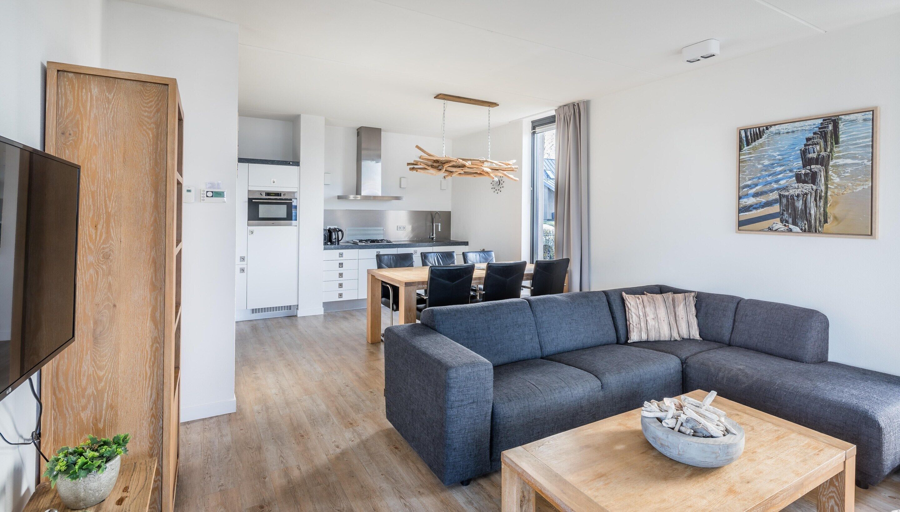 Un salon moderne avec un canapé gris, une table basse en bois et un tableau accroché au mur.