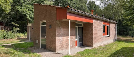 A small brick building with a red roof, a door, and a window.