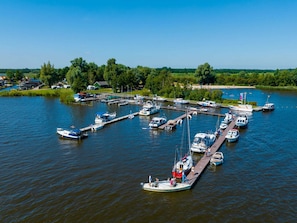 A marina with multiple boats docked at piers, surrounded by greenery and a clear sky. - Chalet in Bergumermeer by the Canal (Sumar)