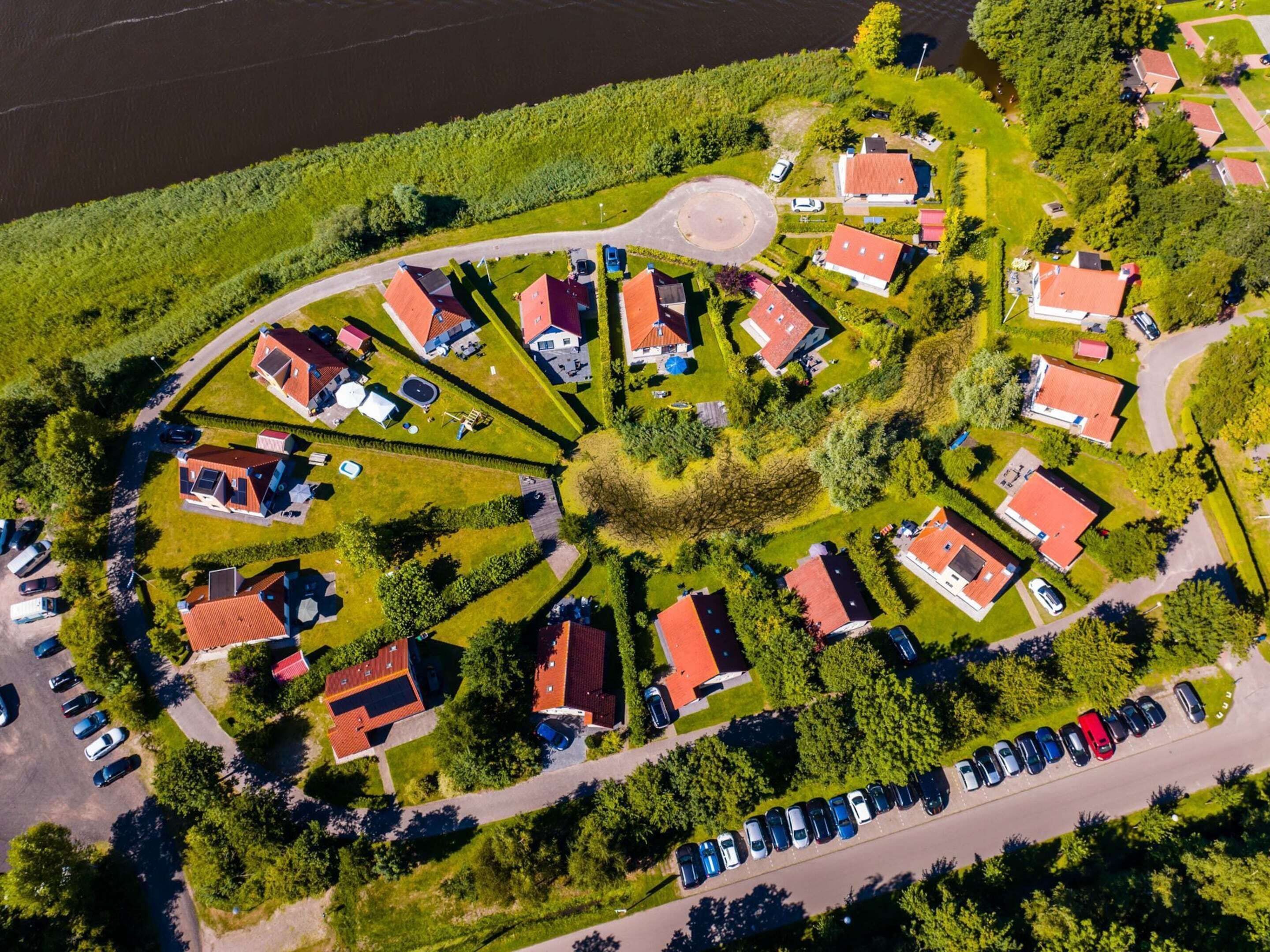 Vista aérea de uma área residencial com casas dispostas em um padrão circular ao redor de um espaço verde central, interligadas por estradas.