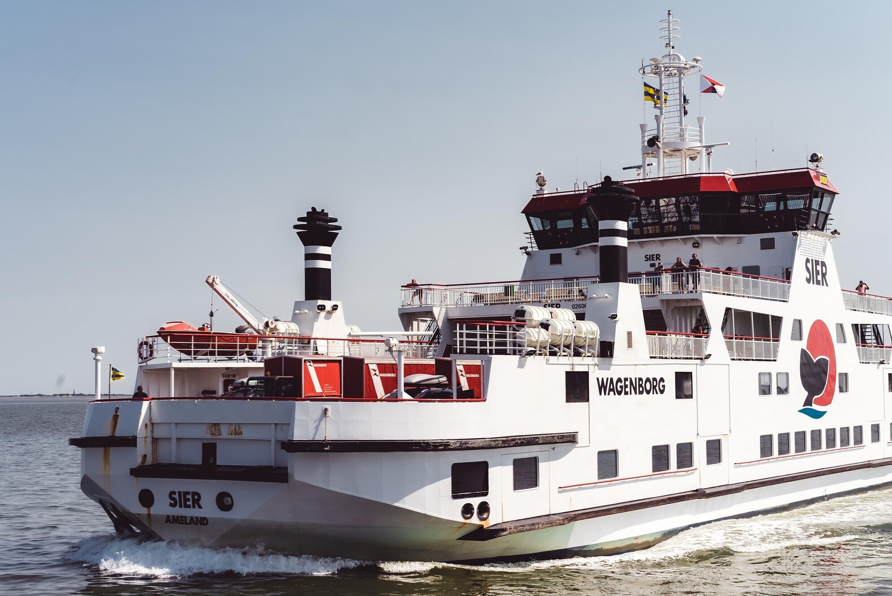 Un ferry con los nombres 'Wagenborg' y 'SIER' en su costado, una torre de control y botes salvavidas.
