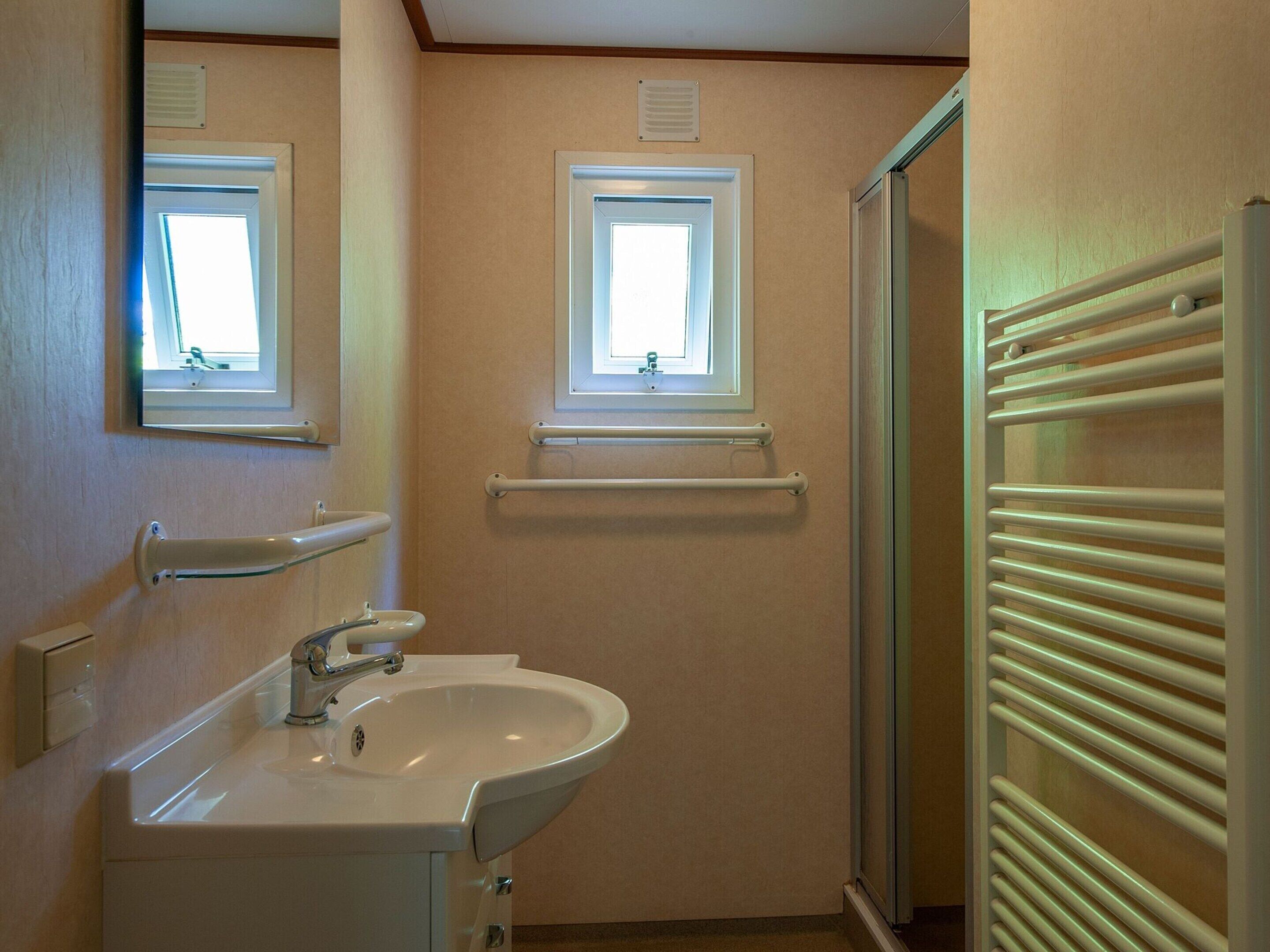 A bathroom with a sink, mirror, window, and towel rack.