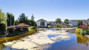 A residential area with houses, a small water body, and surrounding greenery. - Neat Chalet With Microwave Near the Beach in Egmond (Egmond aan den Hoef)