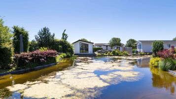 Residents enjoy serene views of a calm water body surrounded by lush greenery and flowering plants.