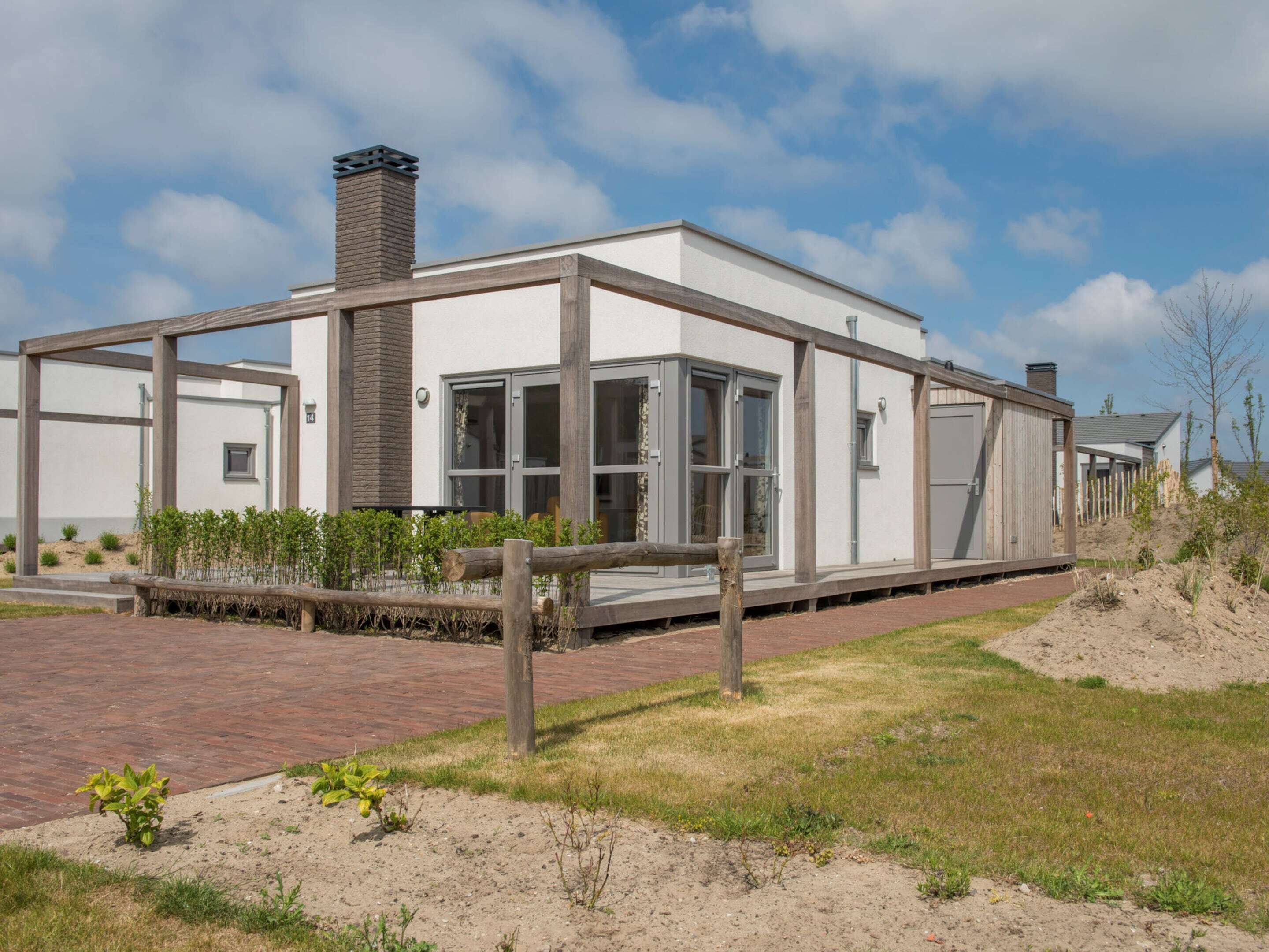 A modern house with a brick pathway leading to a wooden deck.