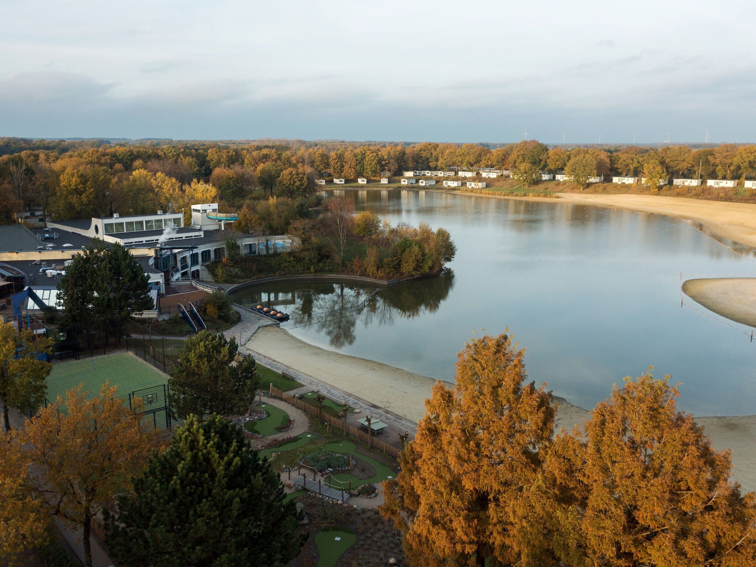 Blick auf einen See mit einem modernen Gebäude, einem Steg und einer Reihe von Mobilheimen.