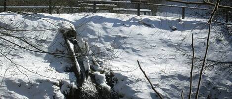 A snow-covered landscape with a wooden bridge and a wooden bench.
