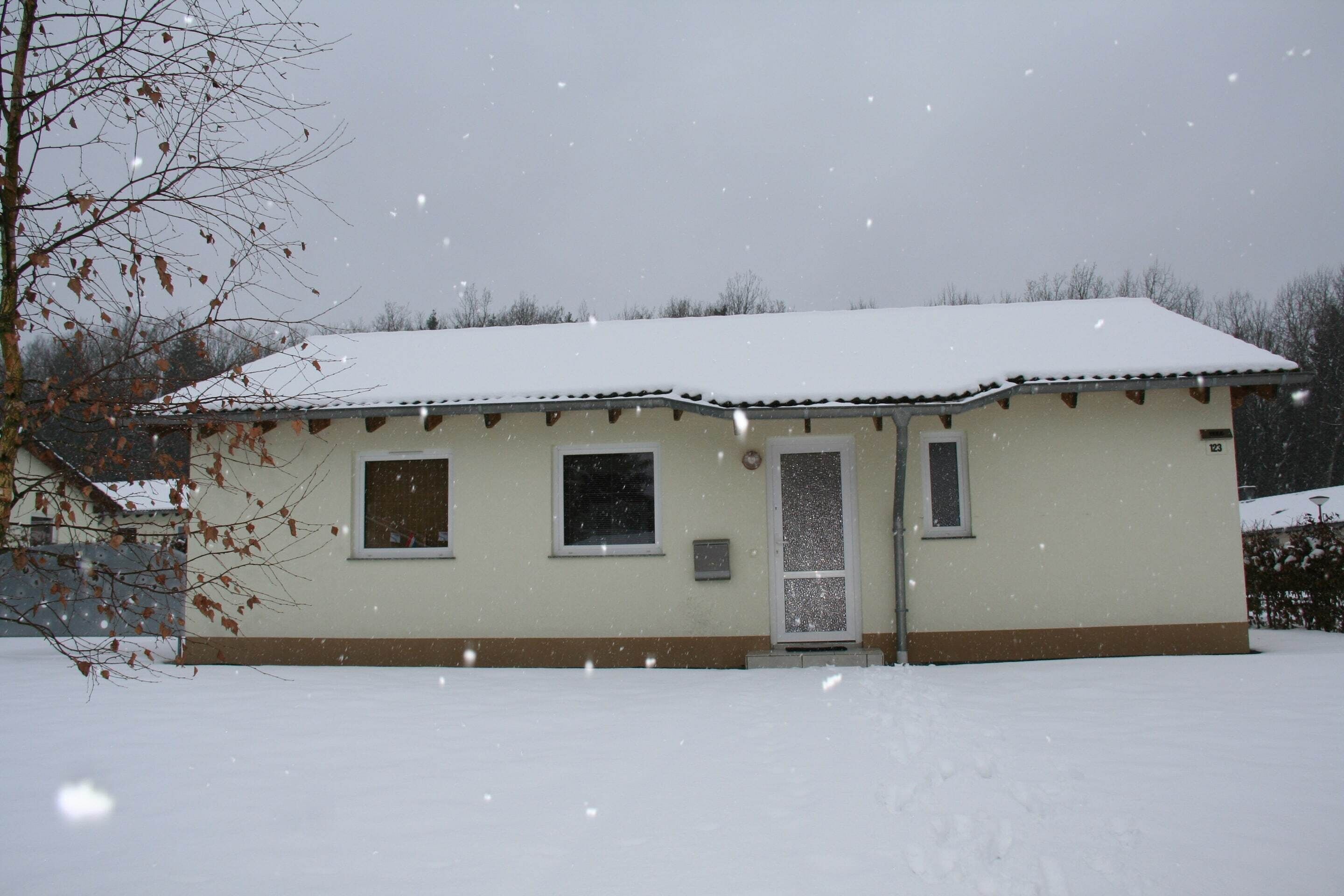 Un edificio de una sola planta con tejado cubierto de nieve y una puerta.