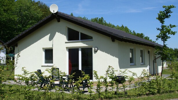 Un bâtiment d’un seul étage, doté d’un toit en pente, d’une antenne parabolique et d’une porte à cadre rouge.
