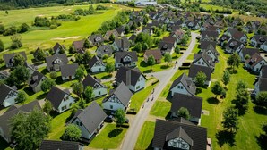 Een woonwijk met huizen in een rasterpatroon, omgeven door groene velden en een golfbaan.