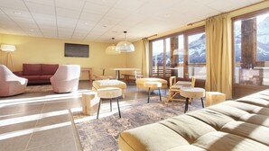 A modern living room with a sofa, chairs, a table, and a view of mountains through large windows. - Chalet in Praroustan With Stunning Mountain Views (Uvernet-Fours)