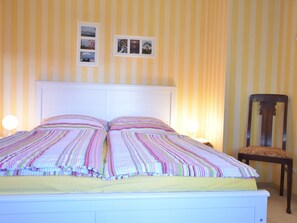 Una cama con cabecera blanca, ropa de cama a rayas y dos lámparas de noche.
