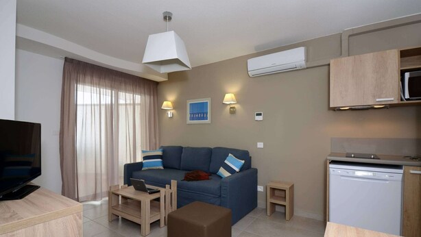 Una sala moderna con sofá, televisor, comedor, cocina equipada con microondas y aire acondicionado.