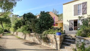 Un mur de pierre, un pot bleu et une maison avec une fenêtre.