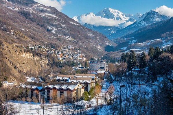 A mountainous town with buildings, a river, and snow-covered peaks. - Mountain Escape With Pool (Brides-les-Bains)
