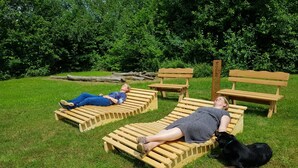 Two wooden lounge chairs in a grassy area with a dense green background. - Holiday Home in Germany With Idyllic Nature (Ronshausen)