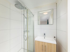 Une salle de bain moderne avec une douche à parois de verre, un lavabo blanc et un meuble en bois.