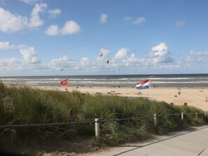 Una playa con banderas, un paseo marítimo y el océano.