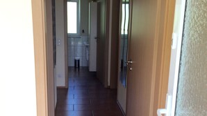A narrow hallway with a tiled floor leading to a kitchen area. - Bungalow in Eifel Near Mountain Trails (Gerolstein)