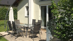 A house with a patio table and chairs, a satellite dish, and a sliding glass door. - Bungalow in Eifel Near Mountain Trails (Gerolstein)