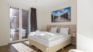 Een hotelkamer met een bed, een schilderij, een nachtkastje en uitzicht door een schuifdeur.