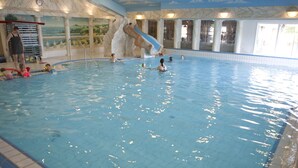 An indoor swimming pool with a water slide, tiled walls, and a mural of a landscape. - Comfortably Furnished Tent Lodge with Stove near Veluwe (Voorthuizen)