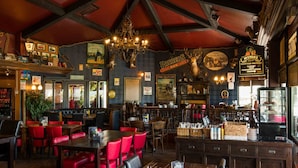 A pub with wooden tables and red chairs, a bar area, and various decorations on the walls. - Modern Chalet With Dishwasher in Noordwijk Near the Sea (Noordwijk)
