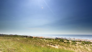 A beach with dunes, a clear sky, and the ocean in the background. - Modern Chalet With Dishwasher in Noordwijk Near the Sea (Noordwijk)
